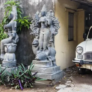 Granite stone carvings and an Ambassador car in a garden at Mamallapuram in Tamil Nadu, India