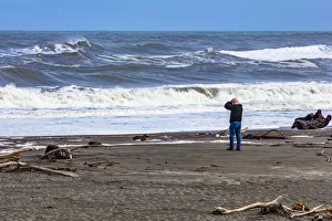 : A photographer photographing the waves on the beach at Hokitika in West Coast, New Zealand